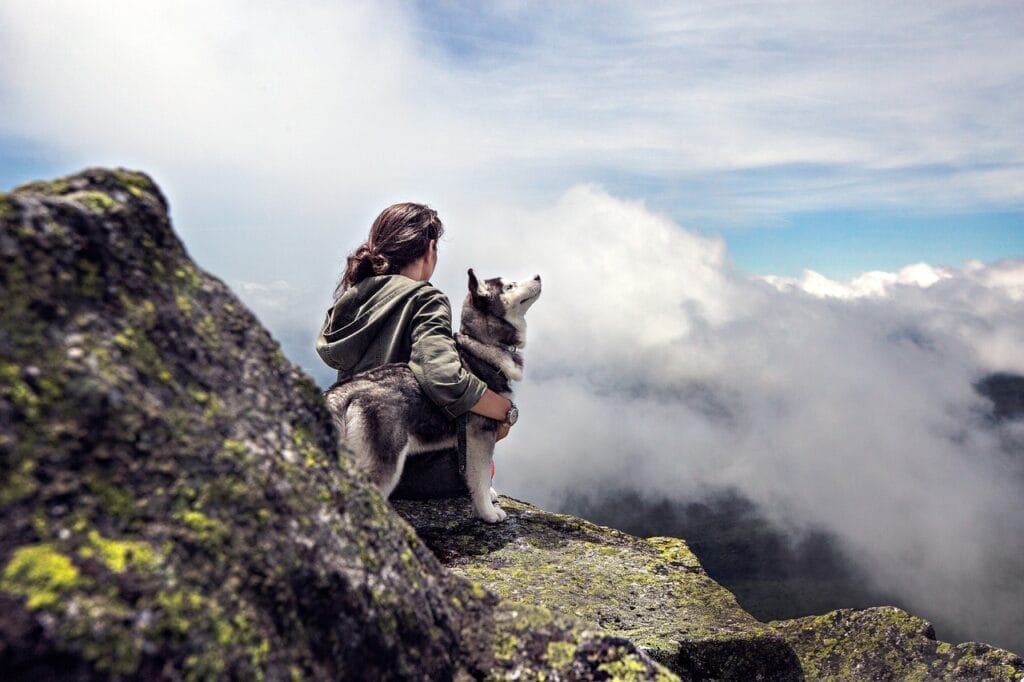 Woman solo hiking with her dog looking at the clouds.