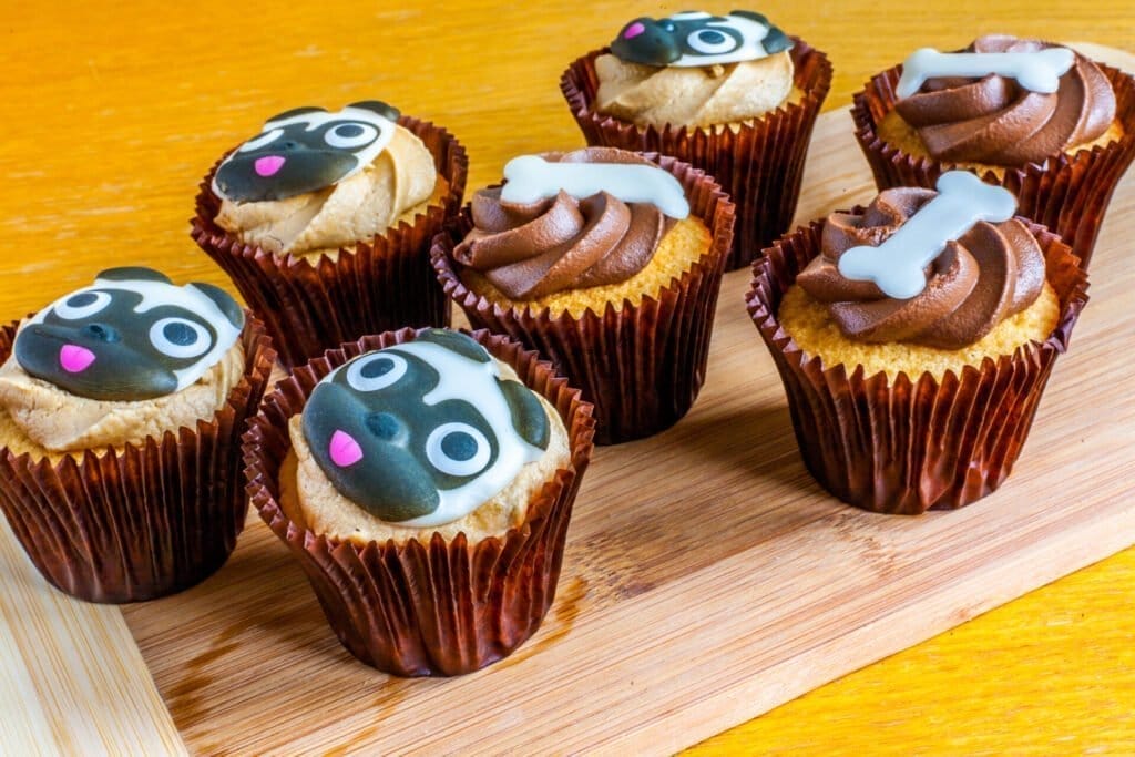 A selection of dog themed cupcakes on a wooden platter.
