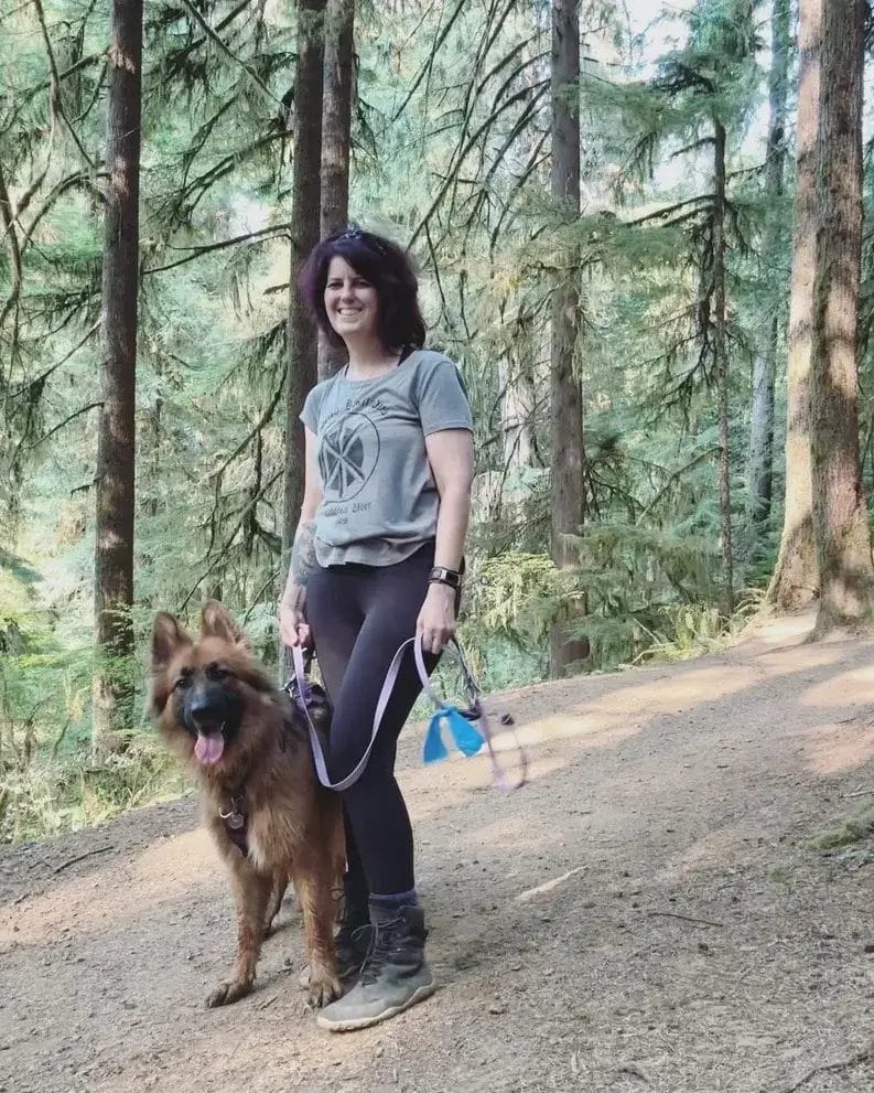 Woman and German Shepherd dog on a hike in the forest.