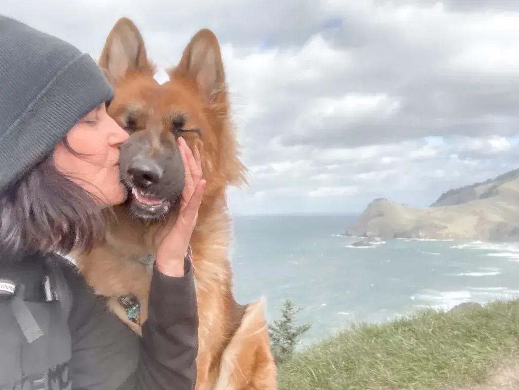 Woman kissing German Shepherd dog on a hike to God's Thumb.