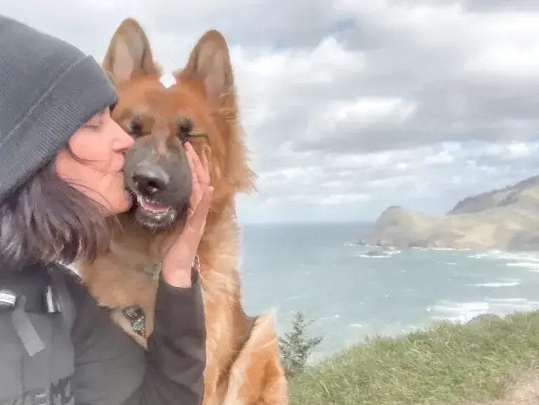 Woman kissing German Shepherd dog on a hike to God's Thumb.