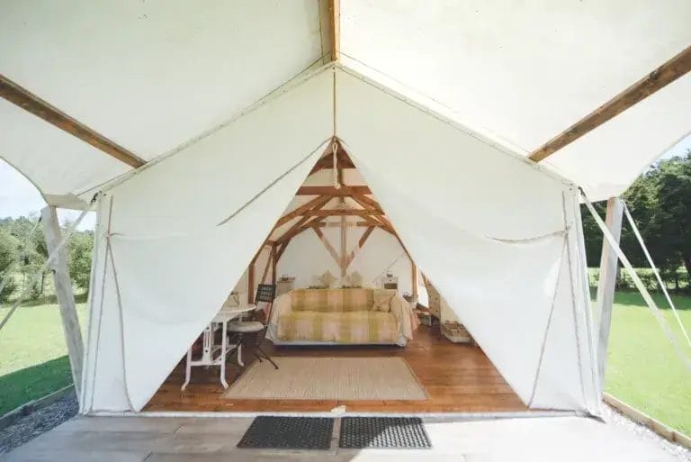 Glamping tent with a couch, tables and wood style floor.