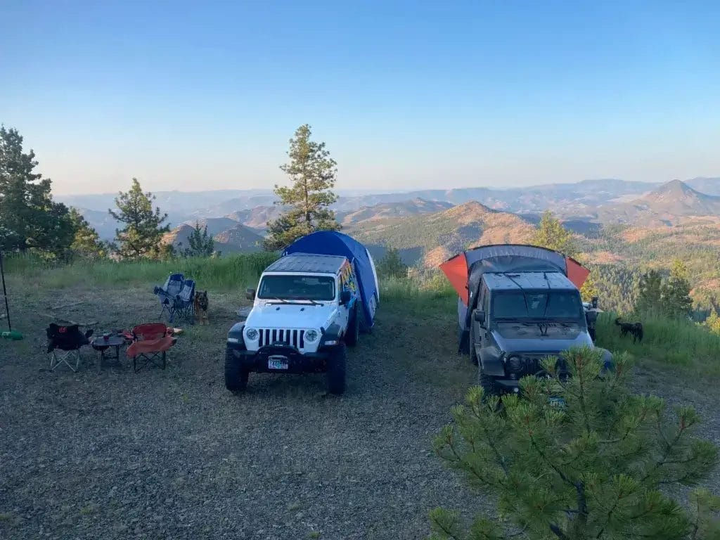 Two Jeep Wranglers with SUV tents parked overlooking mountains in the background.