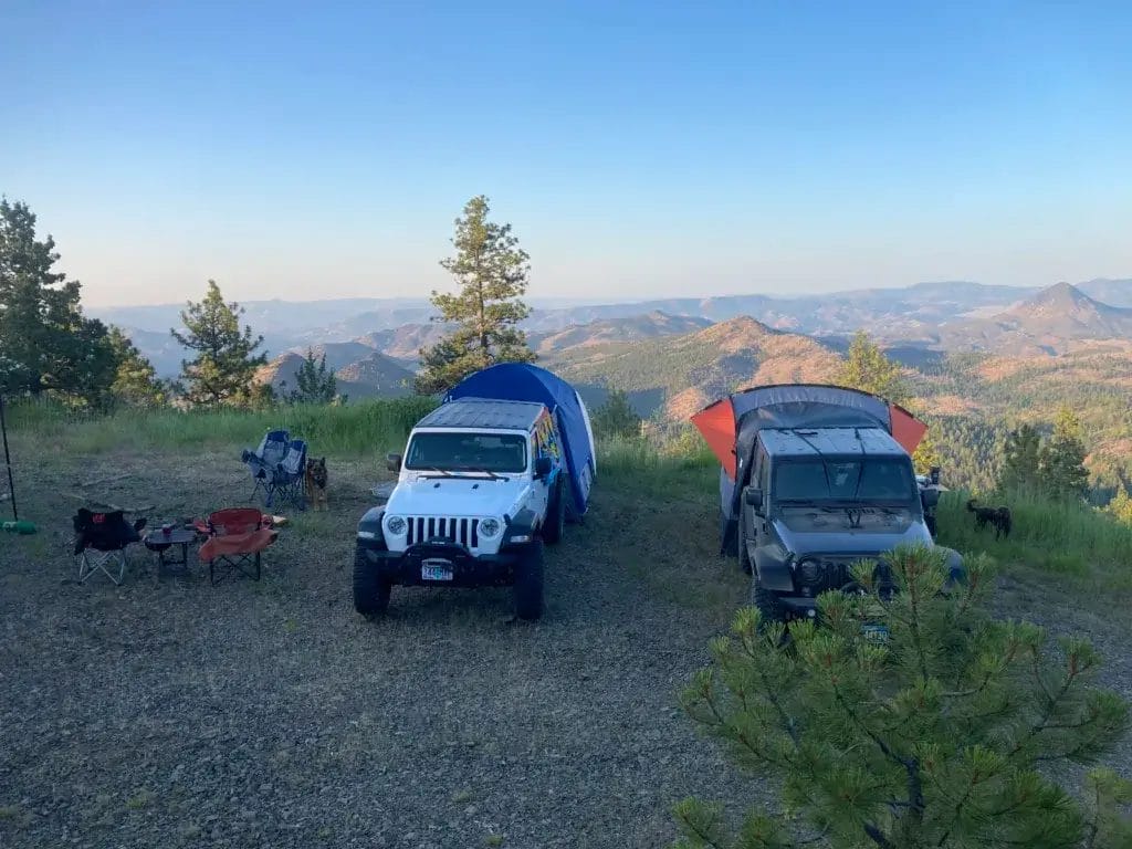 Two Jeep Wranglers with SUV tents parked overlooking mountains in the background.
