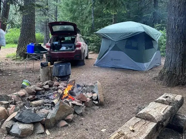 Campsite with a fire pit, parked Subaru Crosstrek and a Gazelle tent.