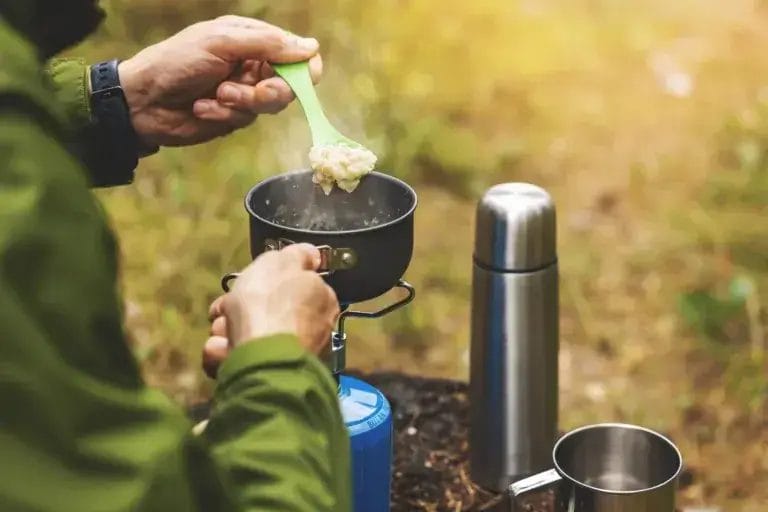 Preparing oatmeal porridge outdoors on a propane burner.