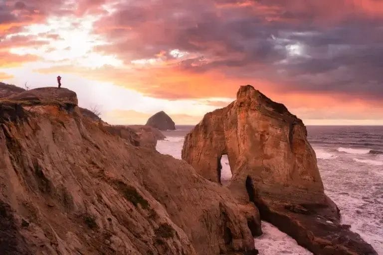Photographer is taking pictures of the beautiful seaside view on the Oregon Coast. Taken in Cape Kiwanda, Pacific City, during a cloudy winter Sunrise.