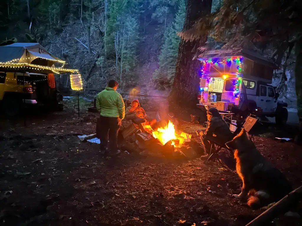 Friends sitting around a campfire winter camping.