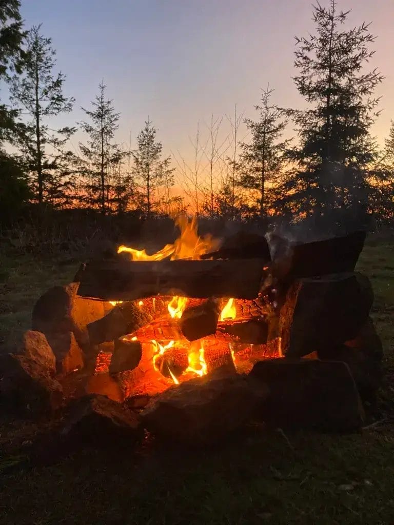 Campfire with an orange sunset sky in the background.