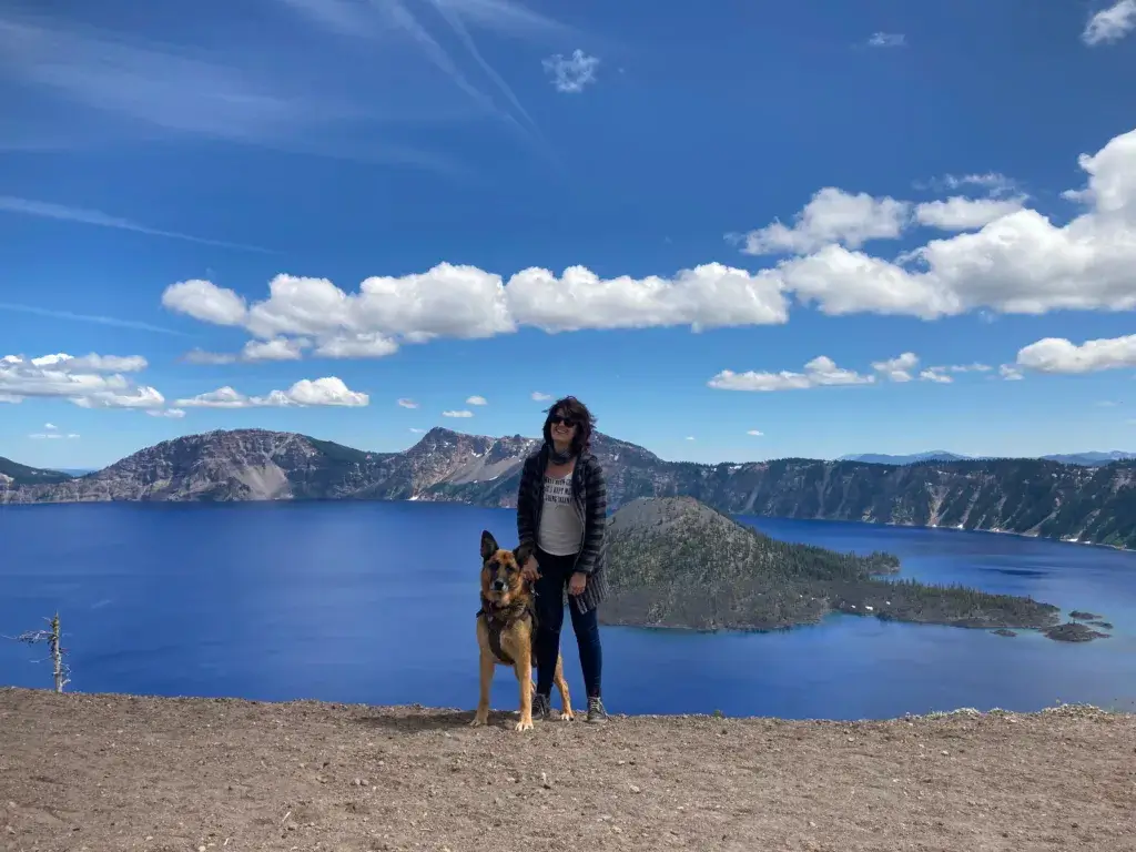 Woman and German Sheperd Dog standing in front of Crater Lake.