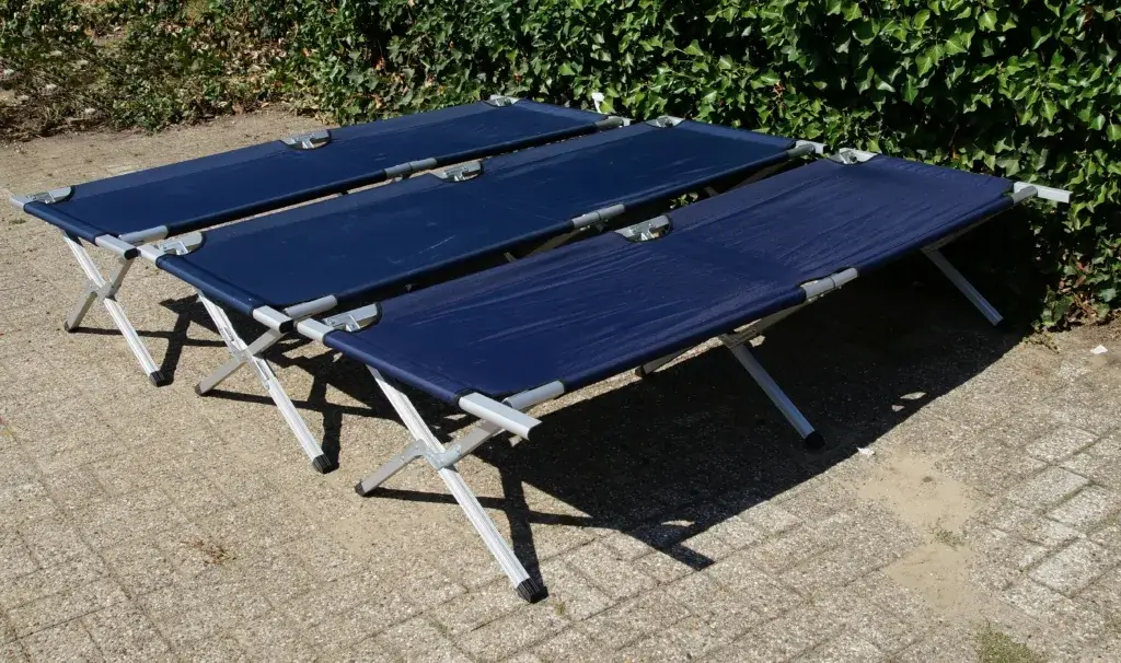 Three blue camping cots side by side.