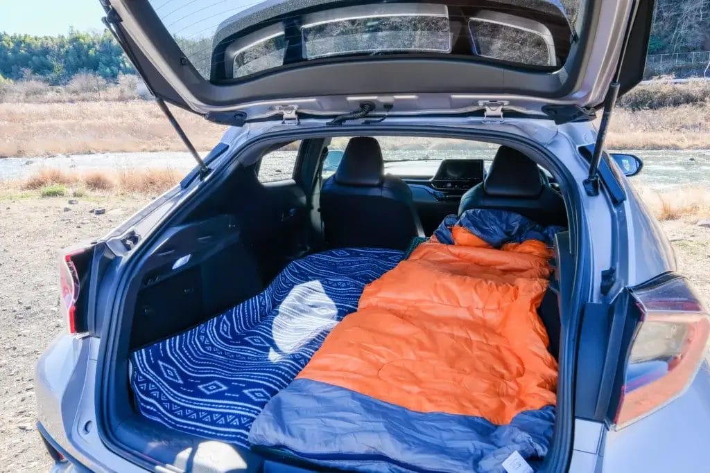 Sleeping bag in the back of a hatchback car ready for camping.