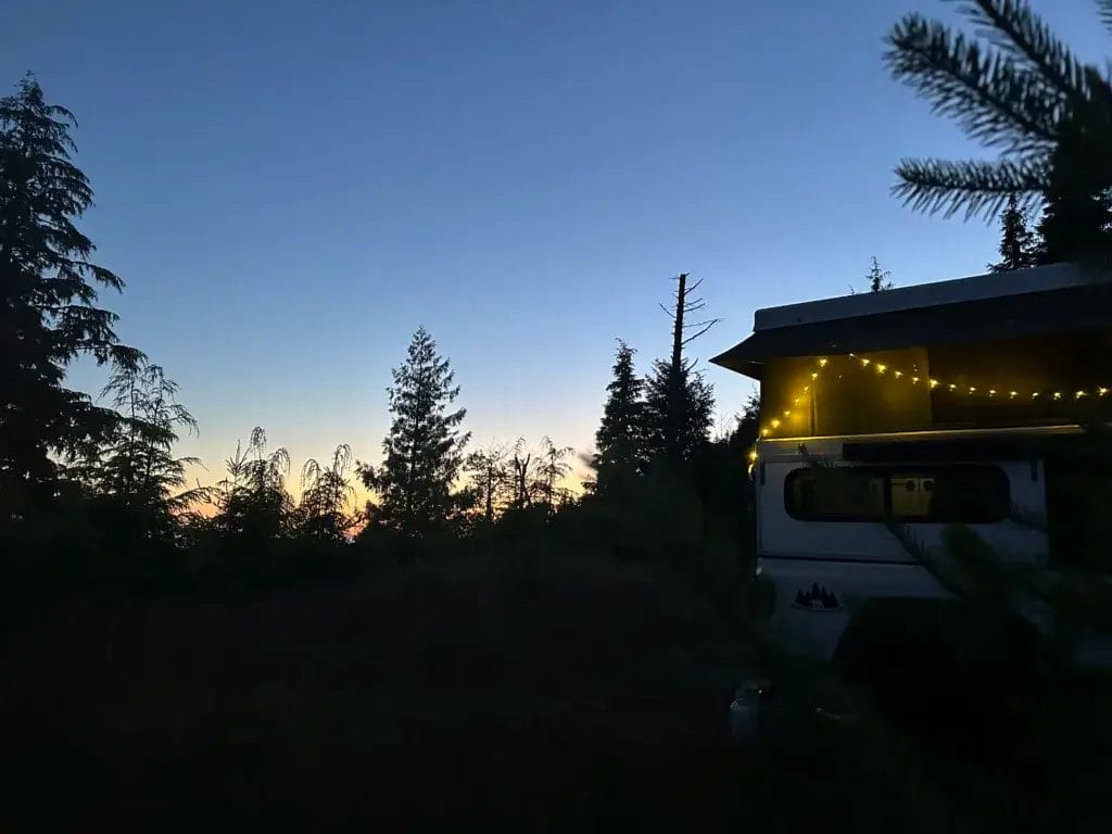 Truck camper with fairy lights at dusk.
