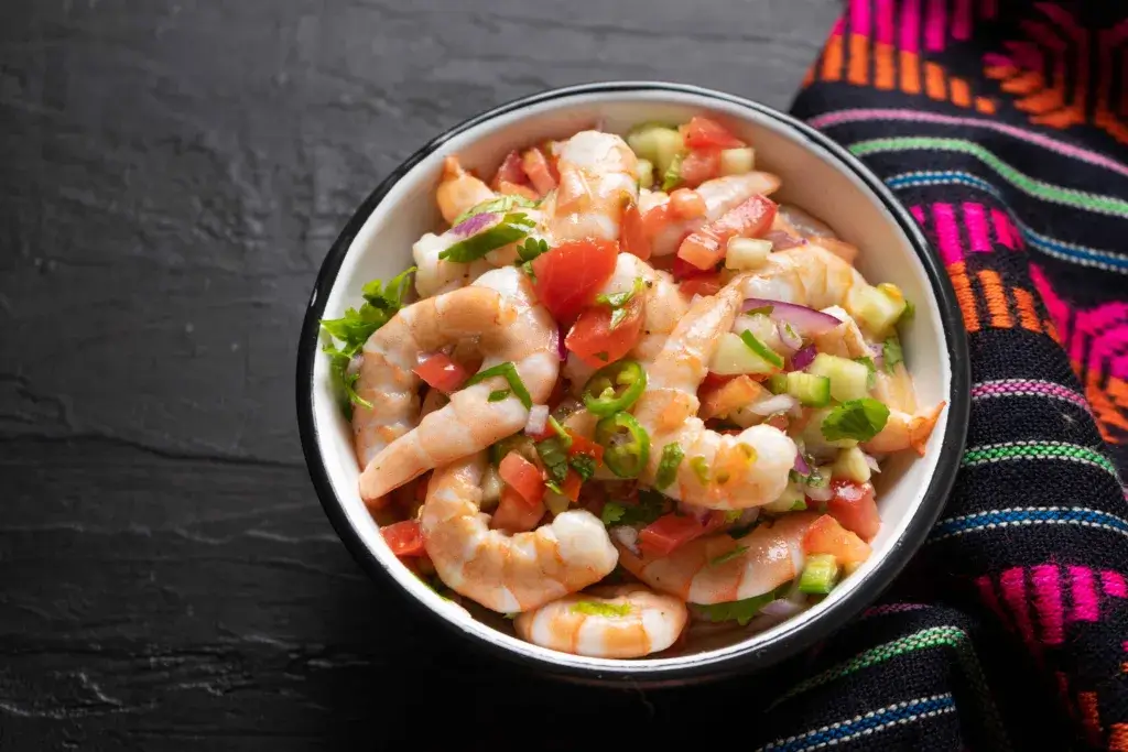Shrimp and vegetables in a bowl on a picnic table.
