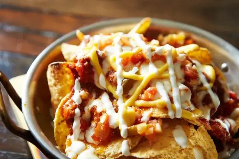 a bowl of nachos with sauce and cheese