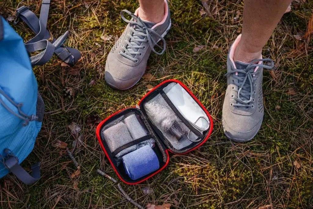 a person's feet standing next to a first aid kit