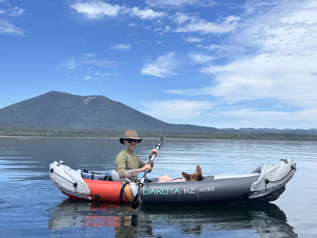 Man and german shepherd dog in an inflatable kayak.