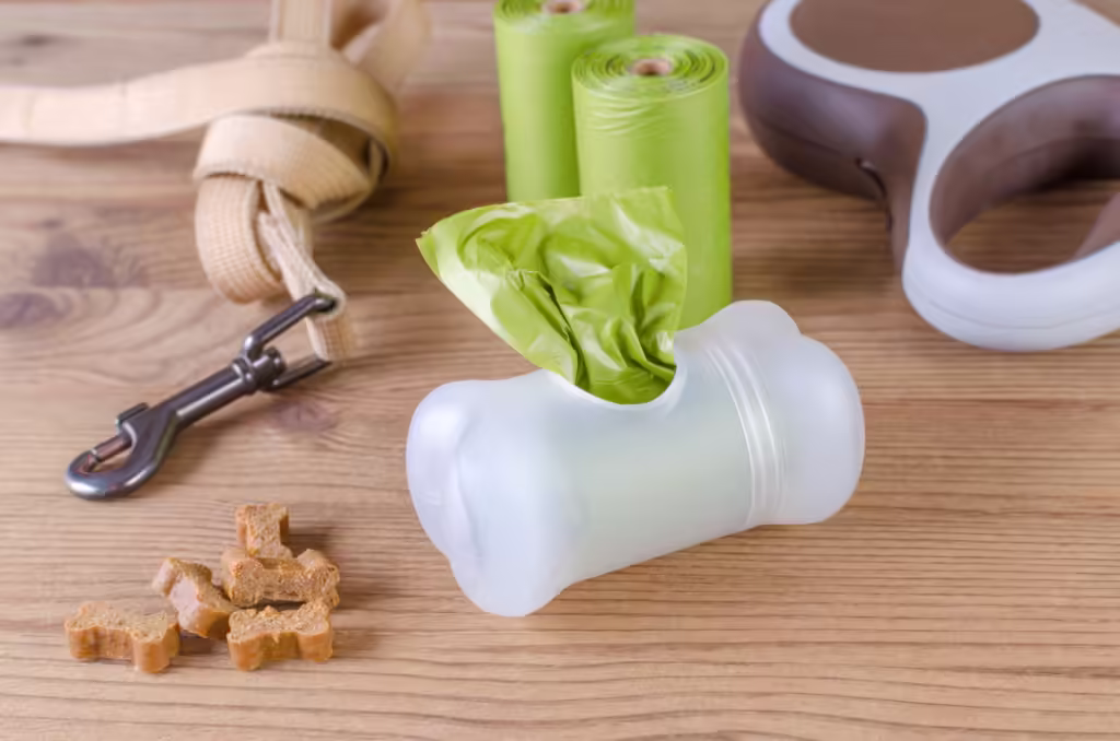 poop bags with leash and dog treats on wooden background, closeup