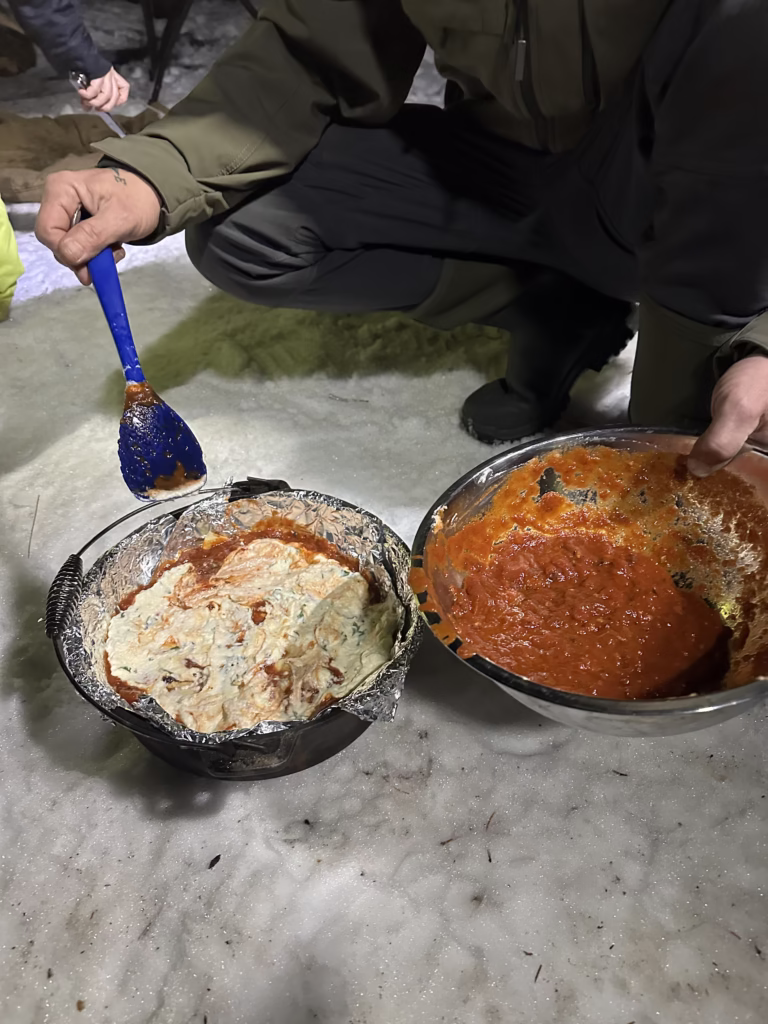 Building dutch oven lasagna on snowy ground.