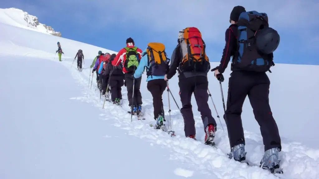 Group of men and women snowshoeing up a mountain.