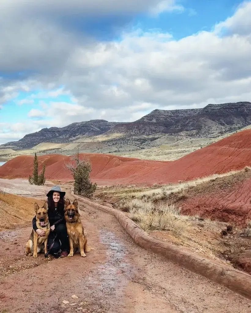 Woman and two German Shepherd dogs on a hike at the Painted Hills in Oregon.