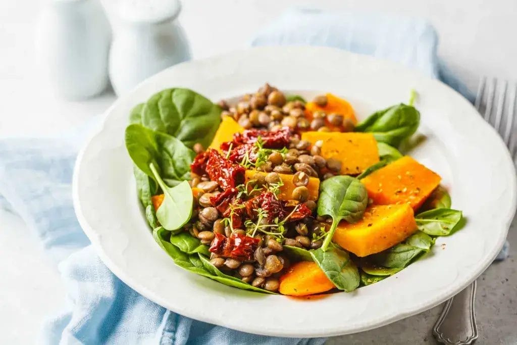 Lentil and roasted vegetable salad in a white bowl.