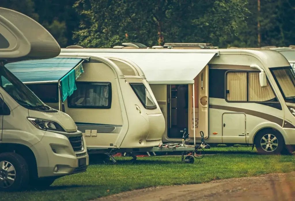 Group of campers parked on a grassy field.
