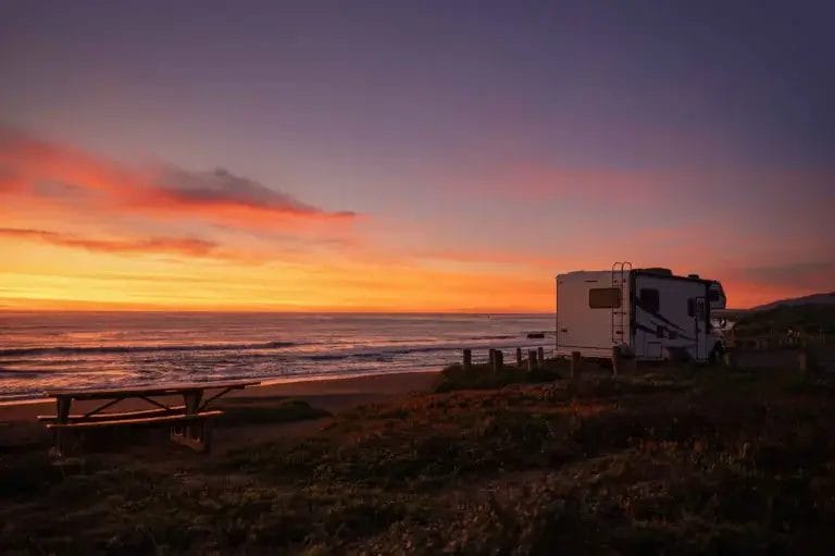 Motorhome boondocking on the beach at sunset.