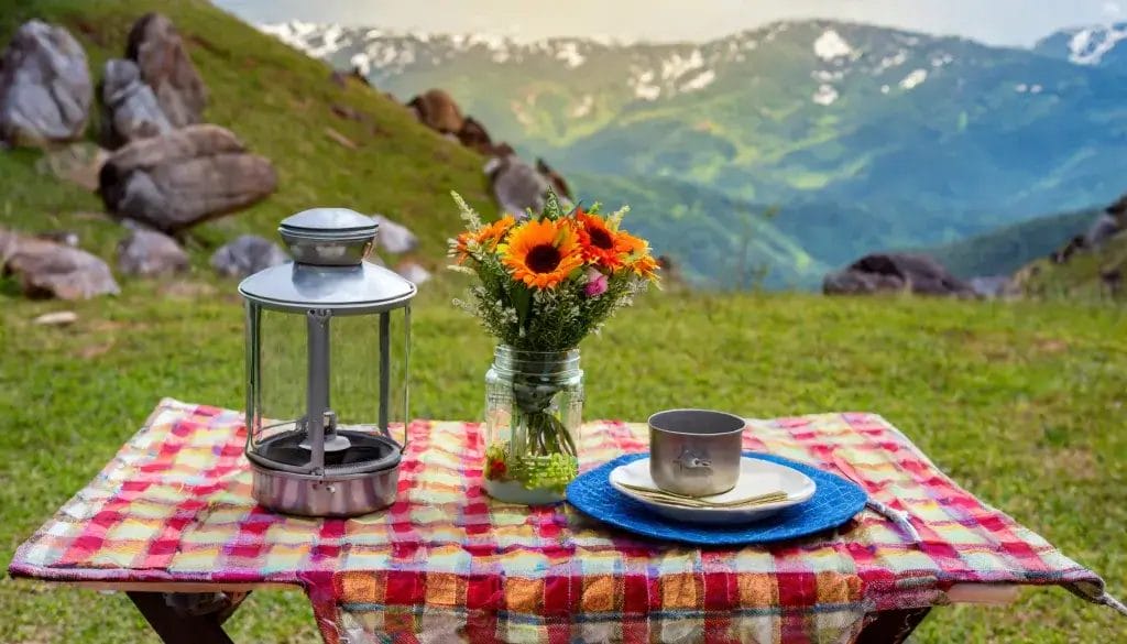 FPicnic table with a colorful table cloth. There is a small camp stove and small pot on the table.