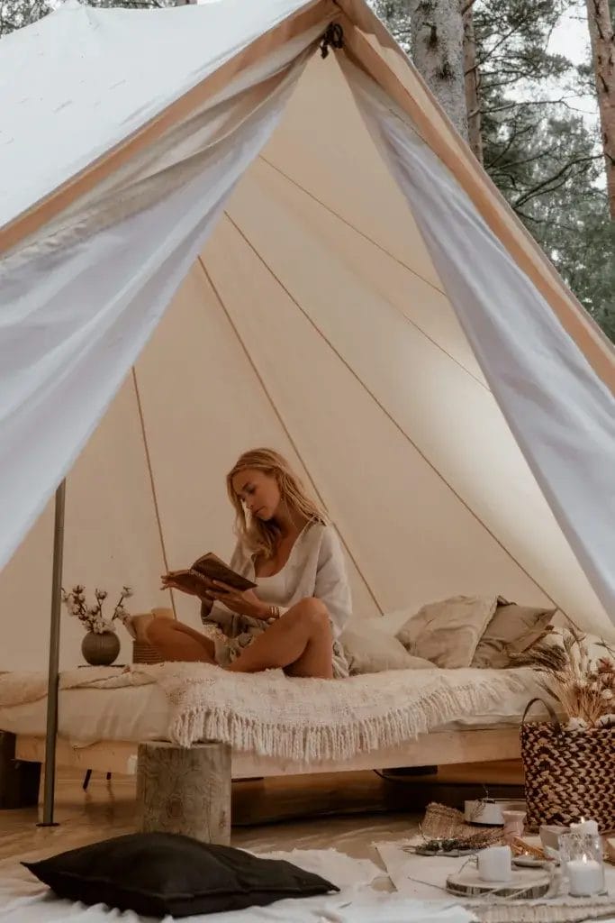 A woman relaxes while reading inside a comfortable glamping tent.