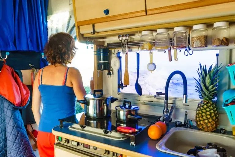 Woman in an organized camper kitchen.