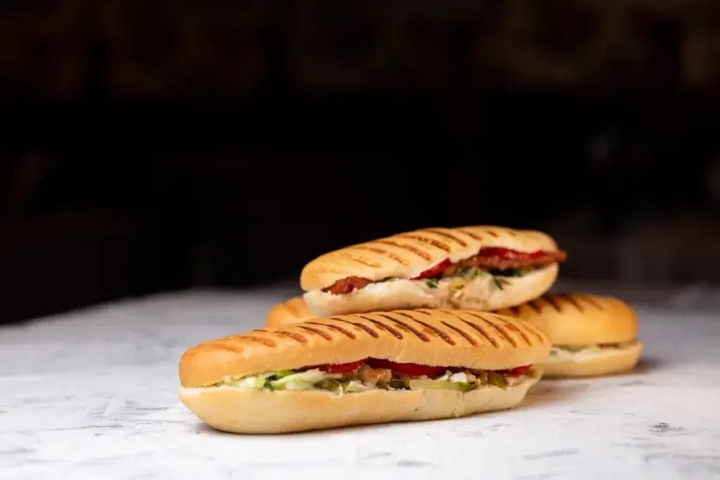 three panini stuffed on a dark background.