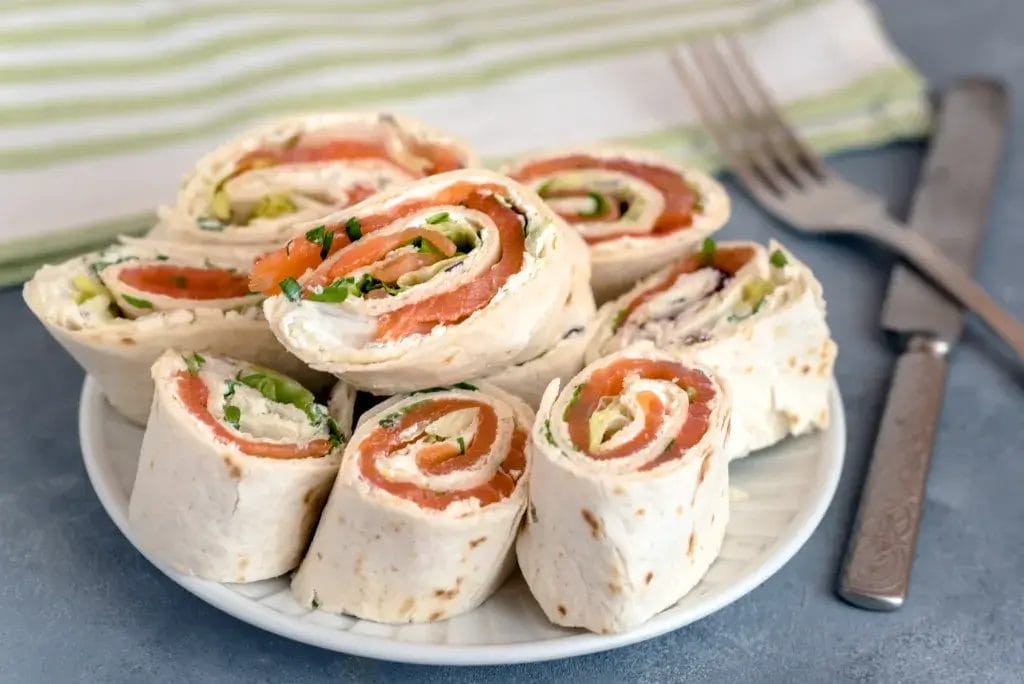 Rolls of thin pancakes with smoked salmon, cream cheese, chives and lettuce.