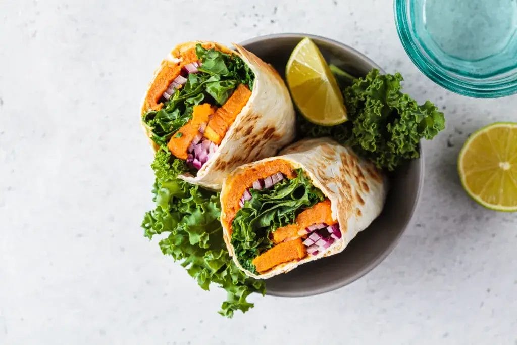 Vegan burrito wrap with sweet potato, kale and onion in bowl. Vegetarian food concept.