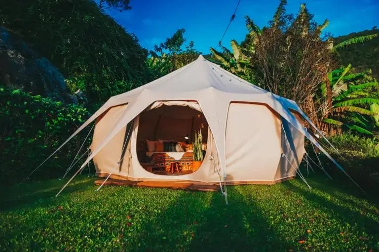 Spacious glamping tent set in a vibrant garden in São Paulo, Brazil, offering a luxurious camping experience surrounded by nature.