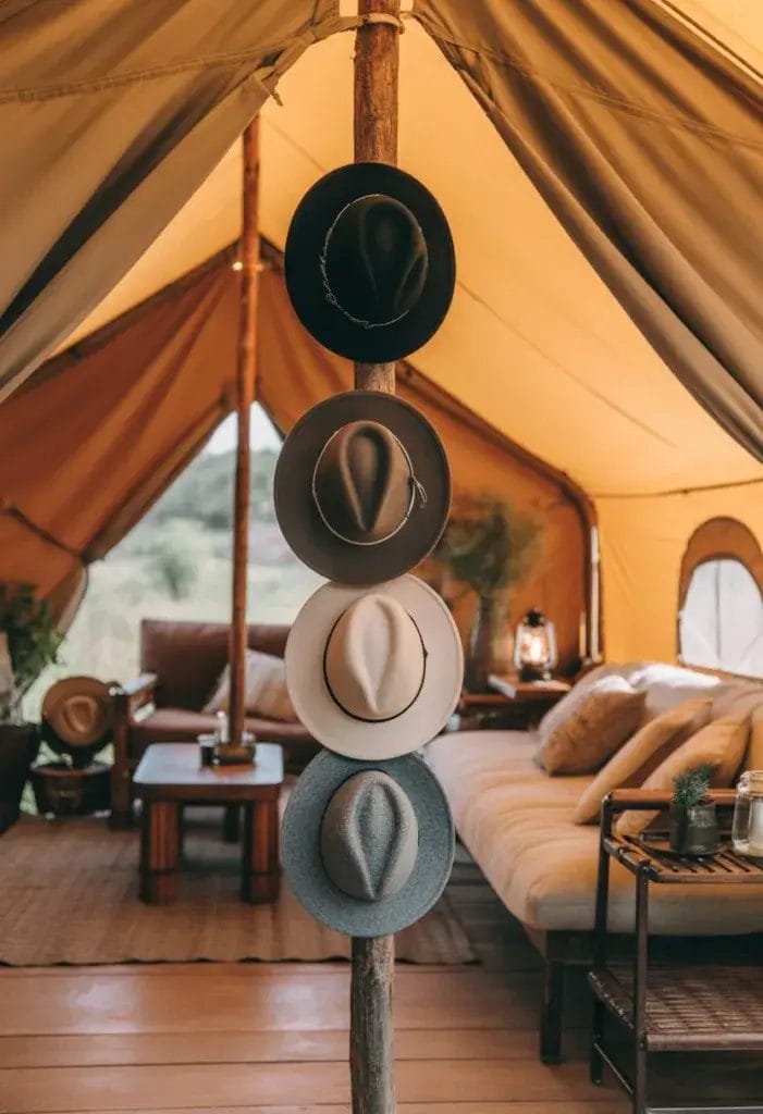 Interior of a glamping tent with hats and lanterns hanging on hooks attached to wooden poles.