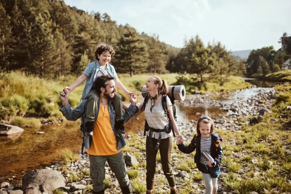 Couple with two children on a scavenger hunt next to a creek in nature.