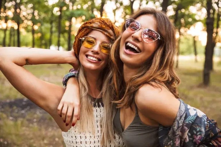 Two young women smiling and laughing in the forest.