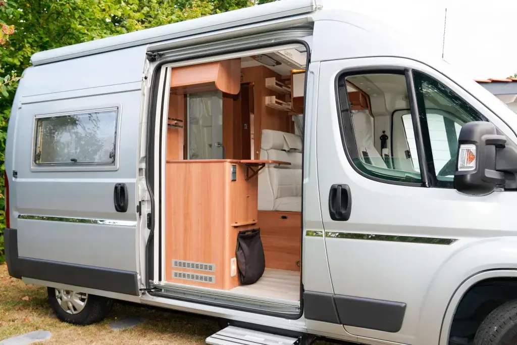 Parked camper van with door open showing interior.