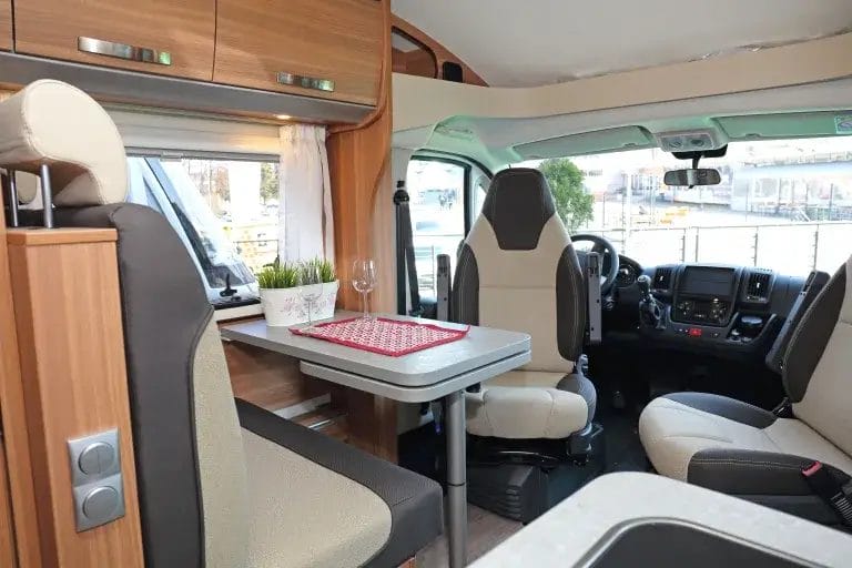Camper van with a small dinette and swivel chairs.