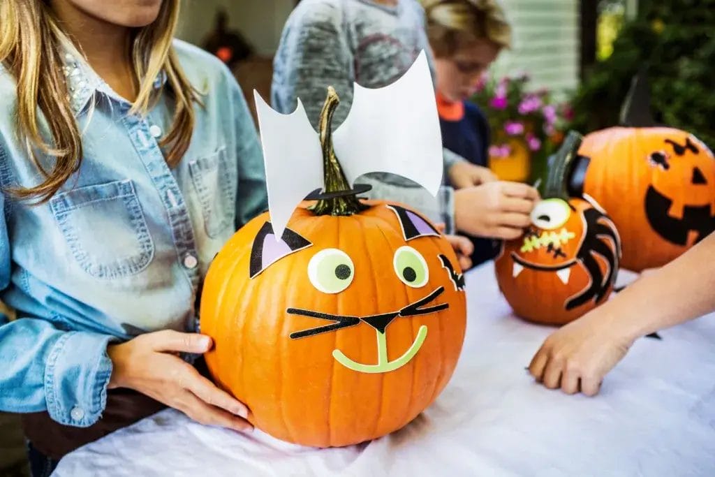 Friends decorating pumpkins like cats.