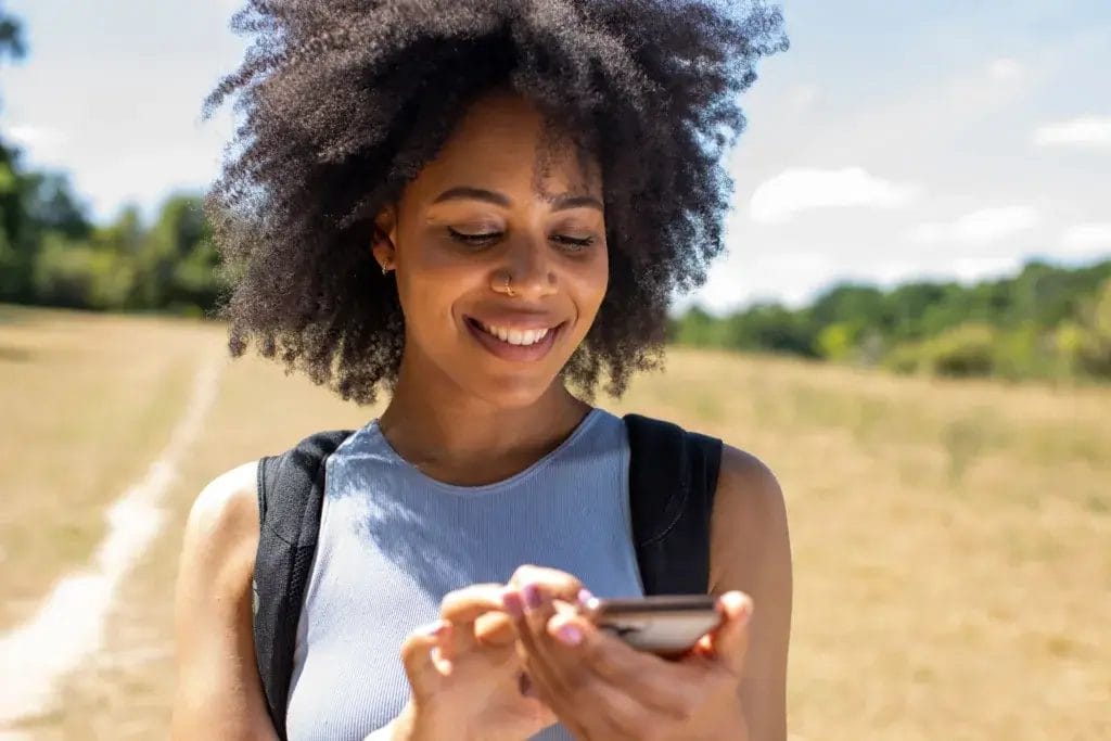 Woman looking at cell phone on a hike.