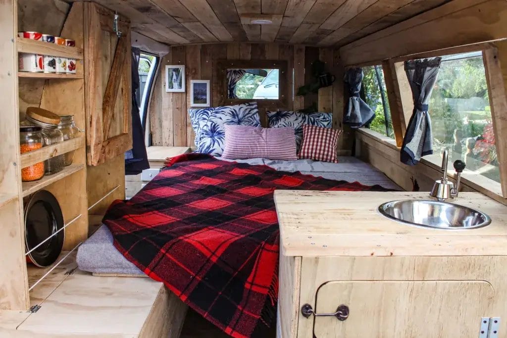 Interior of a built-out camper van incliding kitchen and bed.