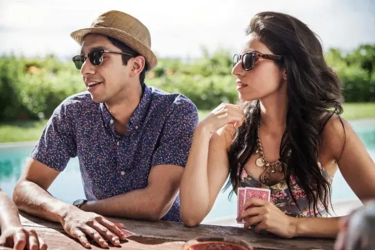 Man and woman sitting at a picnic table playing card games.