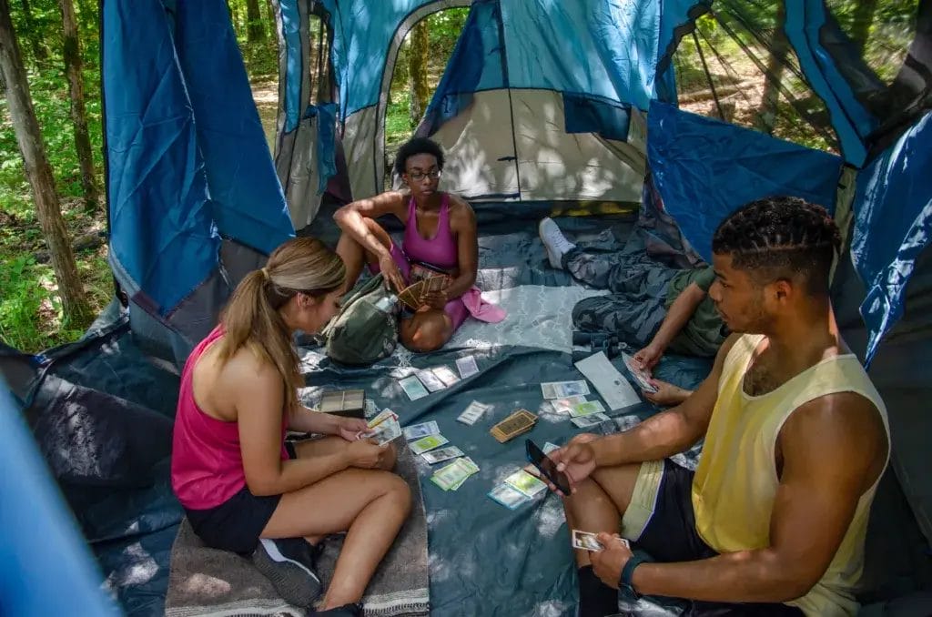 Group of friends playing a card game inside a tent.