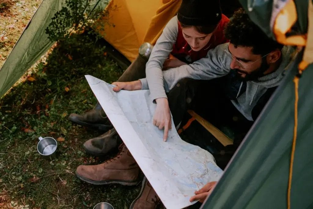 Couple inside a tent examining a map, planning their outdoor adventure.